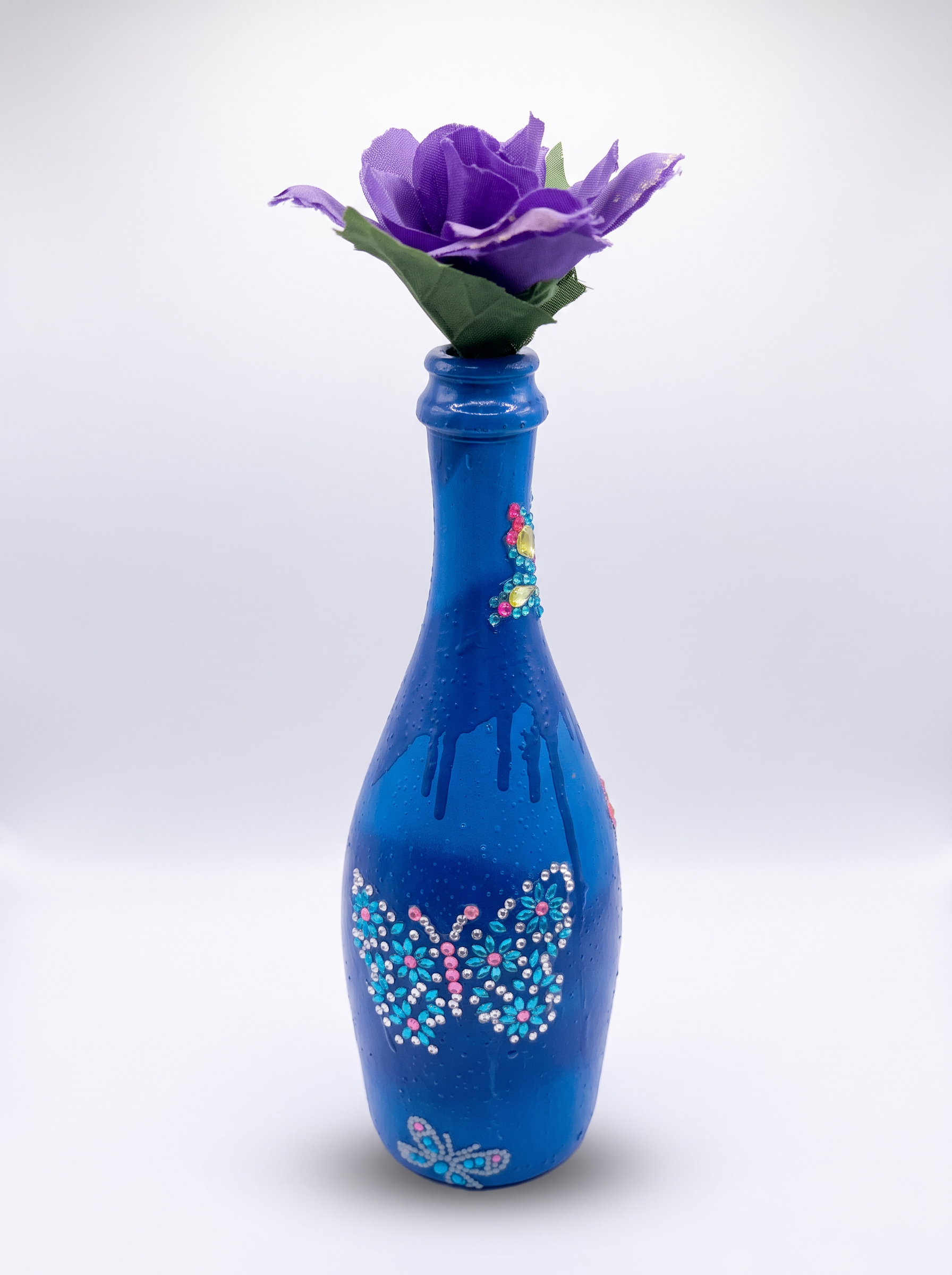 Royal blue bottle vase with a rhinestone butterfly and purple flower