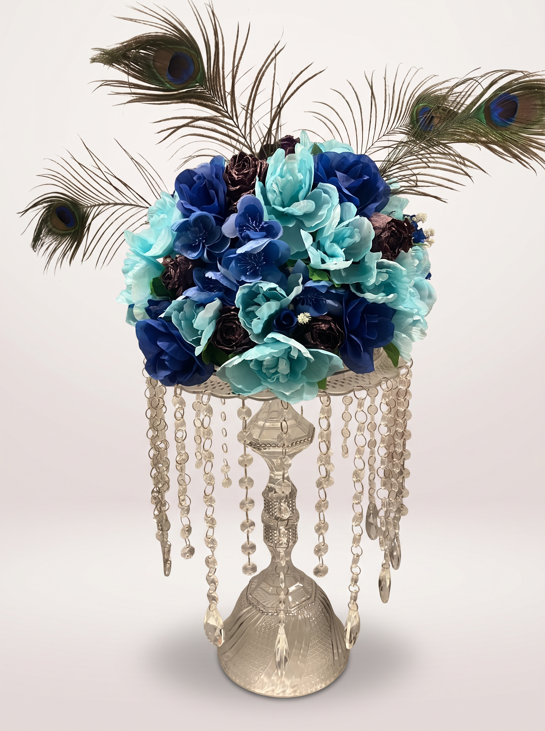 Blue and teal floral centerpiece with peacock feathers and hanging crystals