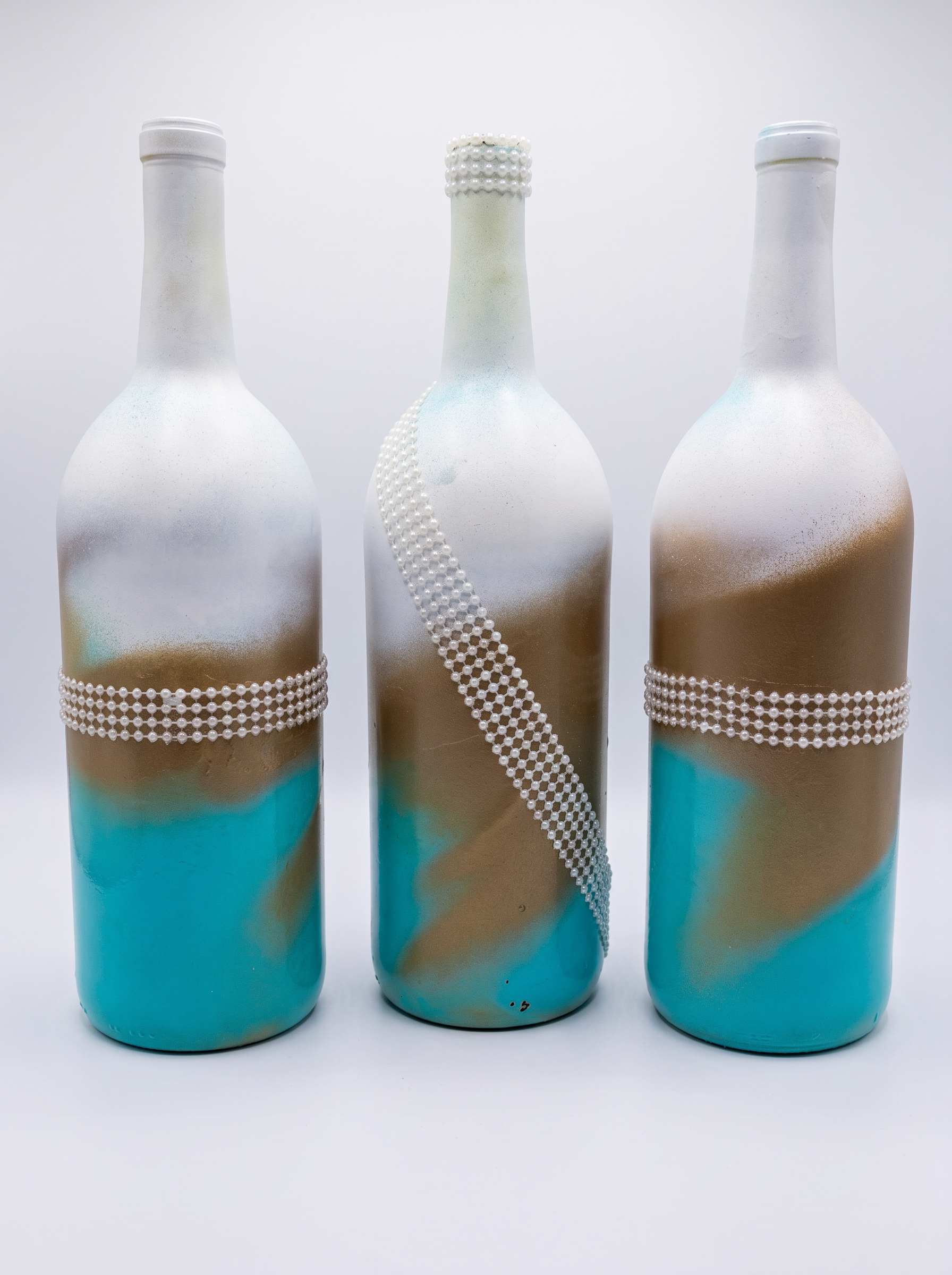 Three teal, gold and white bottles with pearl trim